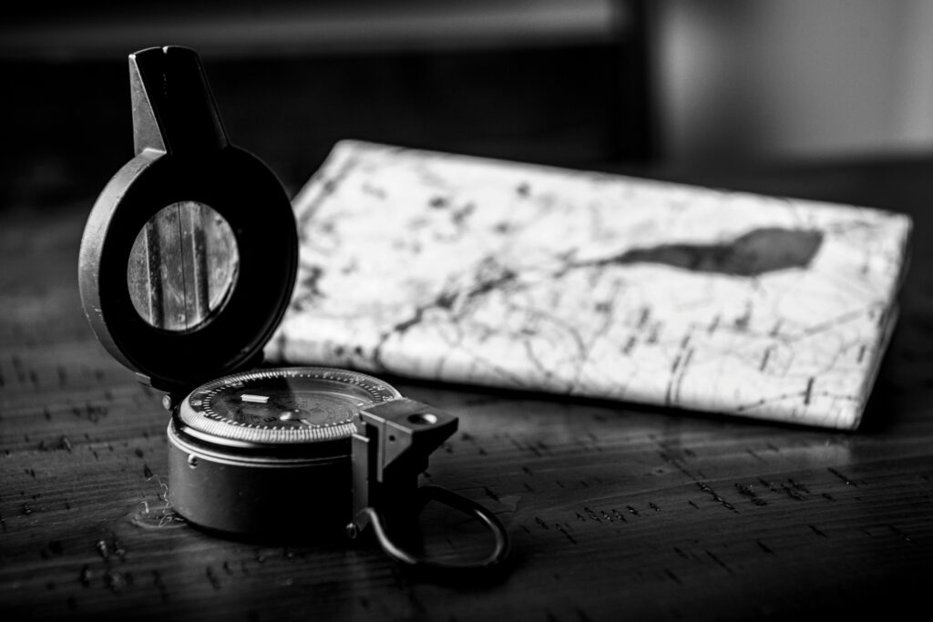 Monochrome close-up of a vintage compass and map, symbolizing navigation and exploration.